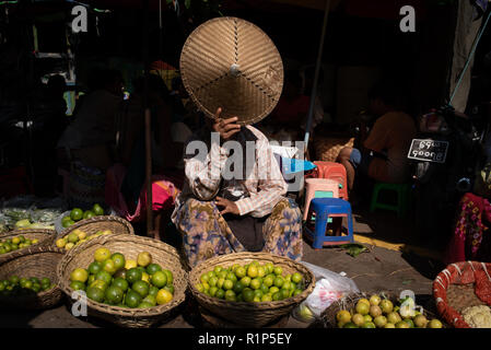 Eine Frau in einem Markt Abschirmung ihr Gesicht von der Sonne, Mandalay, Myanmar. Stockfoto