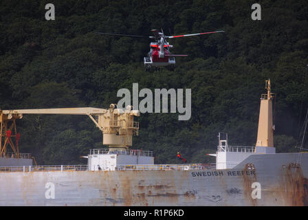 Küstenwache schwebenden Hubschrauber über dem Tanker und ein Hubschrauber Crewmitglied down Winched wird der Unfall zu helfen. River Fal, Cornwall. Stockfoto