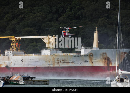 Küstenwache schwebenden Hubschrauber über dem Tanker und ein Hubschrauber Crewmitglied down Winched wird der Unfall zu helfen. River Fal, Cornwall. Stockfoto