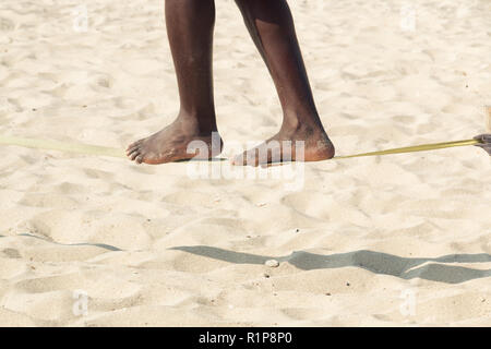 Afro-amerikanischen Kerl üben slack Line am Strand. Slacklining ist eine Praxis, die in der Balance, die in der Regel verwendet Nylon oder Polyester Gurtband gespannt werden Stockfoto