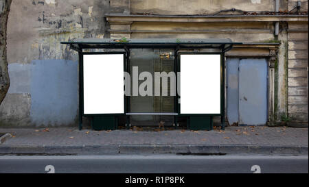 Zwei vertikale weiße Plakate an der Bushaltestelle auf der alten Straße der Stadt. Im Hintergrund Gebäude und Bäume. Mock up. Plakat auf der Straße neben der Fahrbahn. Stockfoto