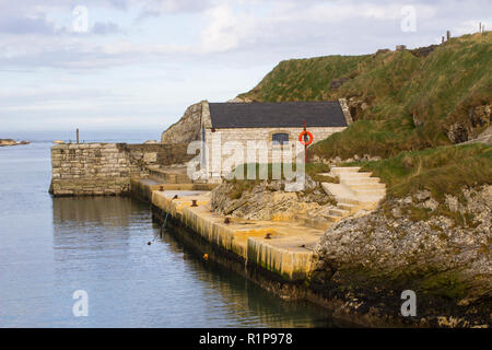 Der kleine Hafen von ballintoy an der Nord Küste von Antrim, Nordirland mit seinen alten Stein Bootshaus an einem Tag im Frühling Stockfoto