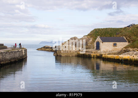 Der kleine Hafen von ballintoy an der Nord Küste von Antrim, Nordirland mit seinen alten Stein Bootshaus an einem Tag im Frühling Stockfoto