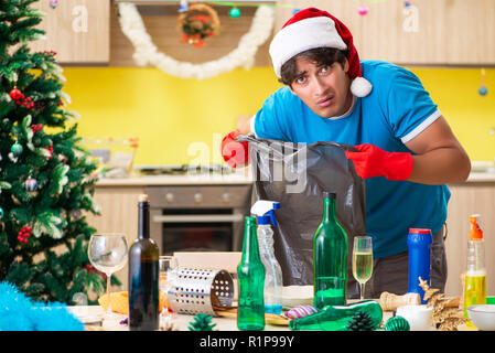 Junger Mann Reinigung Küche nach Weihnachtsfeier Stockfoto