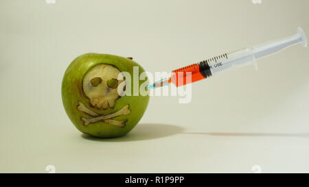 Spritze eingefügt in ein grüner Apfel mit einem gravierten Schädel, repräsentatives Bild von der Verwendung von GVO-Stoffe in Lebensmitteln, Gemüse und Obst Stockfoto