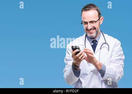 Mittleres Alter senior hoary Arzt Mann texting mit Smartphone über isolierte Hintergrund mit einem glücklichen Gesicht stehen und lächelnd mit einem selbstbewussten Lächeln sho Stockfoto