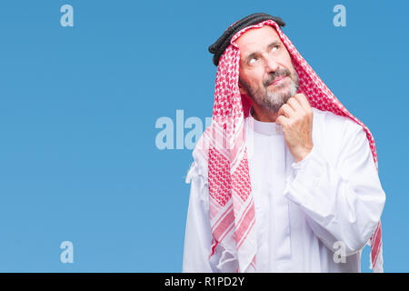 Senior arabischen Mann mit kufiya über isolierte Hintergrund mit der Hand am Kinn über die Frage denken, nachdenklichen Ausdruck. Lächelnd mit nachdenklichen Gesicht. Stockfoto