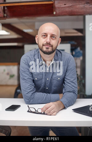Ein junger Mann hoch, 30-39 Jahre, white-collar worker, lehnte sich vor, die Kamera schaut. obere Körper geschossen. Stockfoto