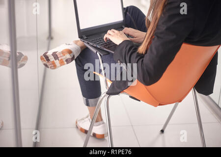 Close-up eine junge Frau, die auf dem Laptop, modernes Bürogebäude im Innenbereich Flur. Rückansicht, zurück. Stockfoto