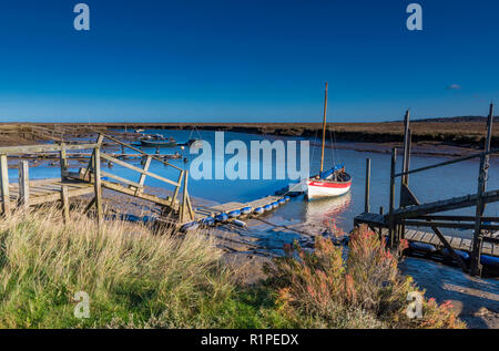Morston Kai und Creek in atmosphärischen North Norfolk. Kleine Boote auf alte hölzerne Stege und Pontons auf einem hellen herbstlichen Tag günstig Stockfoto