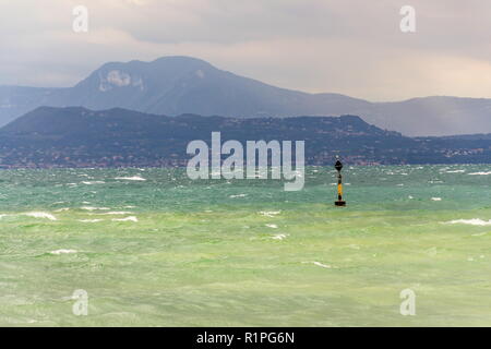 Schwarze und gelbe Boje in turbulenten blau grüne Wellen am Lago di Garda See, windig, bewölkt, Nebel, Sirmione, ItalyBlack und gelbe Boje in turbu Stockfoto