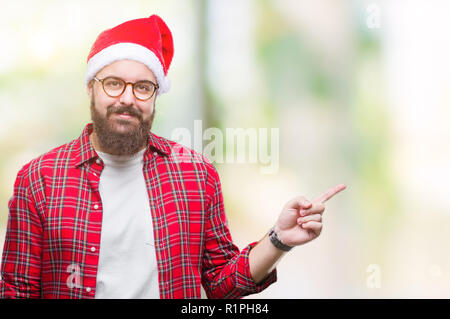 Jungen kaukasischen Mann mit Mütze über isolierte Hintergrund mit einem Lächeln auf dem Gesicht und zeigt mit Finger- und an der Seite ein Blick auf die Stockfoto