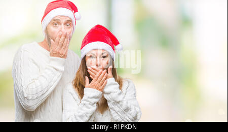 Mittleres Alter spanischer Paar tragen Mütze über isolierte Hintergrund schockiert über den Mund mit Händen für Fehler. Geheime Konzept. Stockfoto