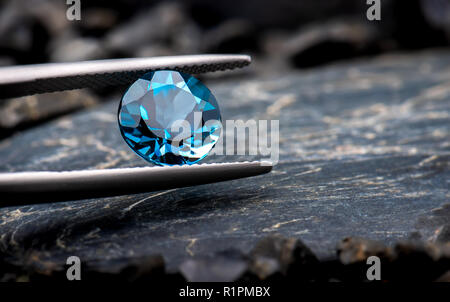 Blauer Topas Edelstein Schmuck Photo mit schwarzem Stein und dunkle Beleuchtung. Stockfoto