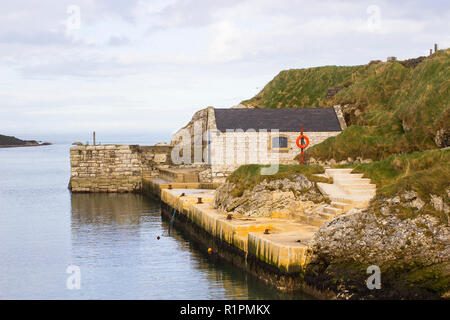 Der kleine Hafen von ballintoy an der Nord Küste von Antrim, Nordirland mit seinen alten Stein Bootshaus an einem Tag im Frühling Stockfoto