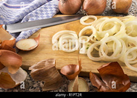 Frisch raw organic Zwiebel Ringe auf einem Holzbrett und einem Messer schneiden Stockfoto