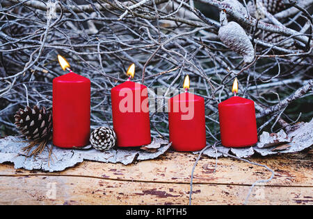 Vier rote Brennende Adventskerzen als Katholische Symbol für Weihnachten. Weihnachtsdekoration mit brennenden Kerzen für die Adventszeit. Grußkarte Konzept Stockfoto