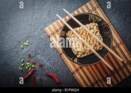 Schwarze Schale, asiatische Instant Nudelsuppe mit und rote Paprika und Frühlingszwiebeln und Essstäbchen Stockfoto