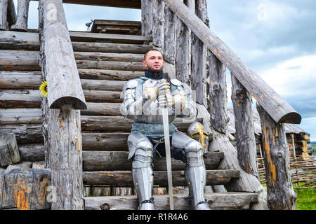 Ritter in der Rüstung auf die hölzerne Treppe. Ritterlichen Rüstung und Waffe Stockfoto