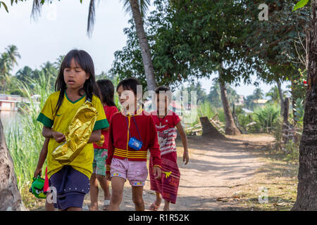 Don Det, Laos - April 22, 2018: Junge Mädchen zu Fuß über einen Pfad neben dem Mekong Fluss zwischen zwei Dörfern auf der 4000 Inseln Stockfoto