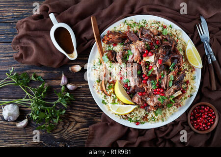 Langsam Braten fallen auseinander mit Couscous Petersilie Salat serviert, mit Granatapfel Samen und frische Minze auf einer weißen Platte mit garavy o streute Stockfoto