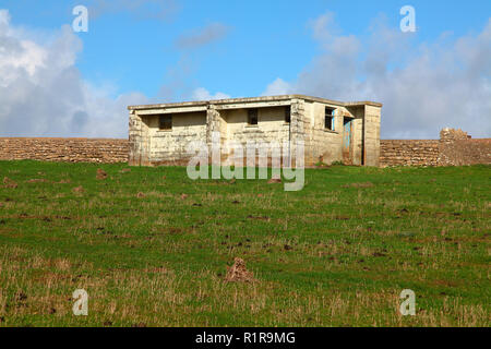 Eine alte verlassene öffentliche Toilette Block in der Mitte eines Feldes isoliert, die hoch oben auf der Spitze eines riesigen Felsen in der Nähe Southerndown Stockfoto