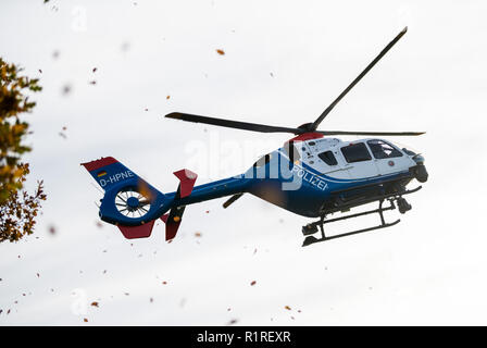 Rastede, Deutschland. 14 Nov, 2018. Ein Hubschrauber der Polizei Niedersachsen fliegt im Tiefflug hinter einem Baum und bläst seine Blätter durch die Luft. Credit: mohssen Assanimoghaddam/dpa/Alamy leben Nachrichten Stockfoto