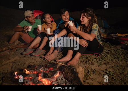 Gruppe von Freunden camping, Sitzen am Lagerfeuer und trinken Kaffee Stockfoto