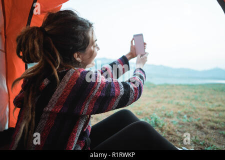 Nahaufnahme einer Frau ein Bild mit Smartphone nach dem Aufwachen am Morgen, im Zelt Stockfoto