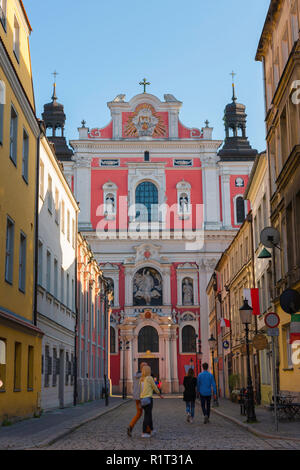 Poznan Straße der Stadt, mit Blick auf die Menschen in der Posener Altstadt zu Fuß in Richtung der barocken Fassade des hl. Stanislaus Pfarrkirche, Polen. Stockfoto