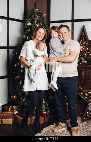 Glückliche Familie mit zwei Kindern am Weihnachtsbaum. Stockfoto