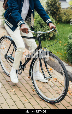 7/8-Ansicht von stilvollen afrikanischen amerikanischen Mann reiten Fahrrad auf der Straße Stockfoto