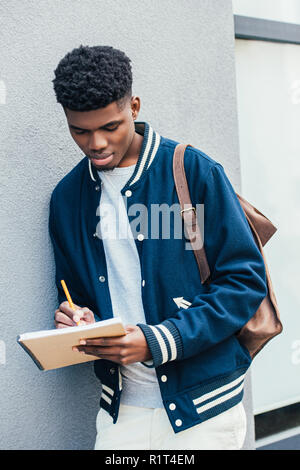 Stilvolle konzentrierte sich afrikanische amerikanische Schüler schreiben in Lehrbuch Stockfoto