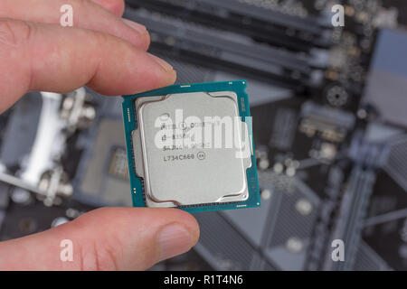 Maykop, Russland - November 9, 2018: der Mann, der Sie die haltefinger Intel Core i3-Prozessor 8. Gen auf Hintergrund motherboard closeup Draufsicht Stockfoto