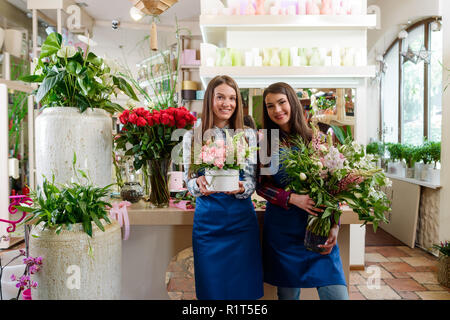 Weibliche Floristen mit blumensträussen Posing Stockfoto