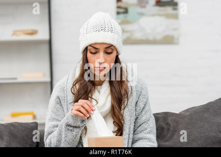 Depressiv kranke Frau in warme Kleidung die Papierserviette aus, beim Sitzen auf der Couch Stockfoto