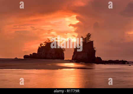 Helles orange Himmel, als die Sonne durch die Wolken an Kemasik Strand, Terengganu, Malaysia Stockfoto