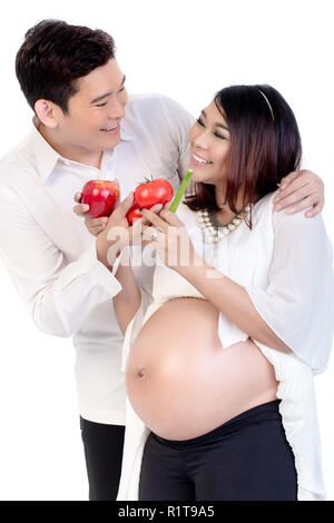 Lächelnder Mann mit Obst und Gemüse zu seiner schwangeren Frau Stockfoto
