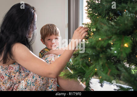 Mutter mit ihrem Sohn Einrichten und Dekorieren australischer Weihnachtsbaum in Ihrem Haus in South Australia Stockfoto