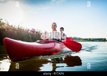 Glückliches Paar rudern Kajak fahren auf dem See Stockfoto