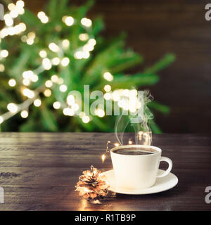Tasse schwarzen Kaffee auf hölzernen Tisch im Café. Weihnachtsbeleuchtung und gold Girlande für den Hintergrund. Stockfoto