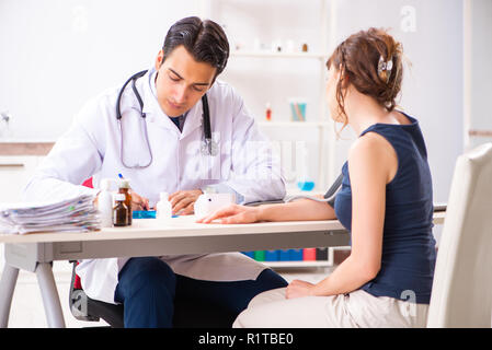 Der junge Arzt prüfen Frau Blutdruck Stockfoto