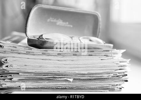 Große Stapel von Zeitungen und Lesebrillen in Ledertasche, Business Konzept Stockfoto