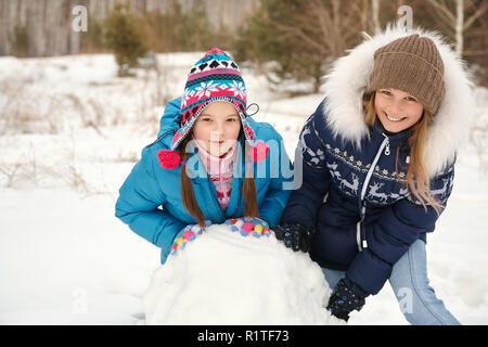 Zwei weibliche Freunde einen Schneemann bauen. lustig Mädchen auf einem Spaziergang im Winter im Freien Stockfoto