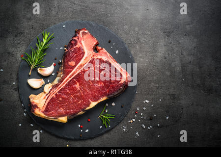 T-bone Rindersteak auf Schwarz mit Gewürzen. Stockfoto