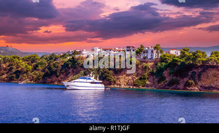 Sonnenuntergang über der Stadt Skiathos, Griechenland. Luxusyacht in der Bucht von Skiathos, in der Nähe des Hafens Stockfoto