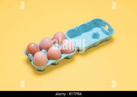 Halbes Dutzend kostenlose Sortiment Bio braune Eier im Karton. Sechs braune Eier in der Kiste Behälter auf einem hellen Pastell gelb Hintergrund Stockfoto