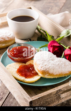 Valentinstag Frühstück mit Kaffee, herzförmigen Bun, berry Jam und Rosen auf einem Tablett Stockfoto