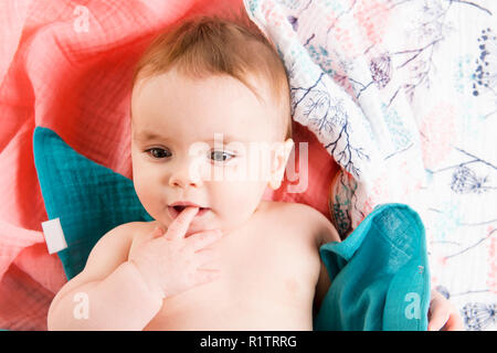 Das Baby unter einem Handtuch. Alter von 10 Monaten. Es ist auf einem weißen Hintergrund isoliert Stockfoto