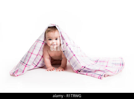 Das Baby unter einem Handtuch. Alter von 10 Monaten. Es ist auf einem weißen Hintergrund isoliert Stockfoto